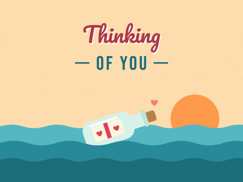 Thinking of you message in a bottle with a heart note bobbing on teal waves at sunset