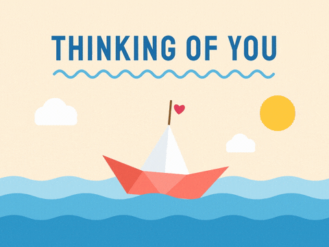 Thinking of you origami paper boat with a heart flag sailing over rolling blue waves