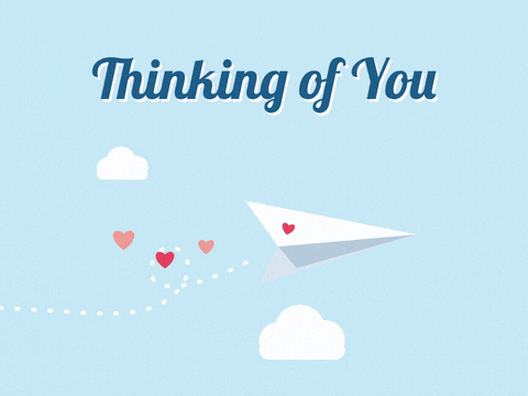 Thinking of you paper plane flying past clouds and leaving a trail of hearts on a pale blue sky