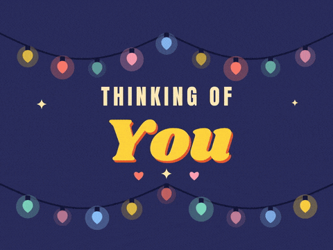 Thinking of you lettering glowing between two strings of colourful fairy lights on navy