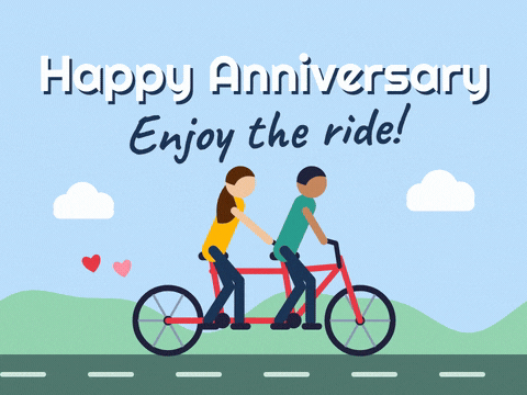 Happy anniversary, enjoy the ride message with a couple pedalling a red tandem bike past green hills