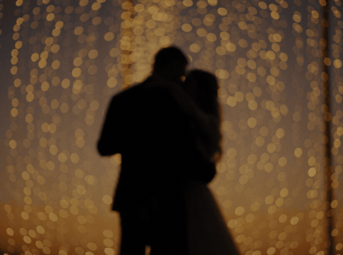 Couple silhouetted against warm bokeh lights with So Happy For You Two message, animated wedding GIF